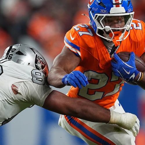 Denver Broncos running back J.K. Dobbins, right, runs for a first-down as Las Vegas Raiders defensive tackle Jonah Laulu makes the stop in the second half of after an NFL football game Thursday, Nov. 6, 2025, in Denver. (AP Photo/David Zalubowski)