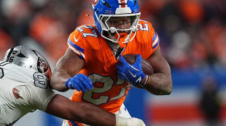 Denver Broncos running back J.K. Dobbins, right, runs for a first-down as Las Vegas Raiders defensive tackle Jonah Laulu makes the stop in the second half of after an NFL football game Thursday, Nov. 6, 2025, in Denver. (AP Photo/David Zalubowski)
