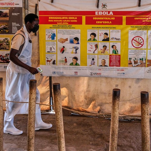 A health worker walks past Ebola warning and instruction posters at a temporary health clinic at the Mpondwe border crossing linking Uganda and the Democratic Republic of the Congo, Thursday, June 4, 2026. (AP Photo/Hajarah Nalwadda)