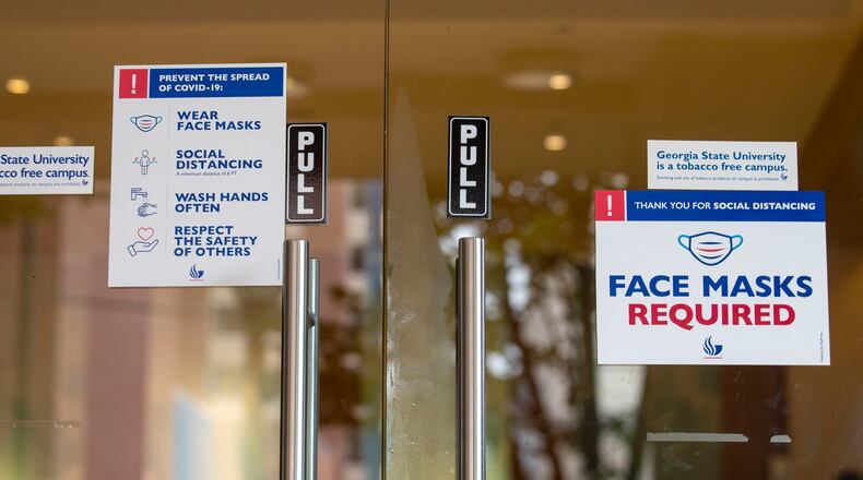 08/24/2020 - Atlanta, Georgia - Signs advising individuals to practice social distancing and to wear a face mask are displayed on a Georgia State University building door during the first day of classes at Georgia State University in Atlanta, Monday, August 24, 2020. (ALYSSA POINTER / ALYSSA.POINTER@AJC.COM)