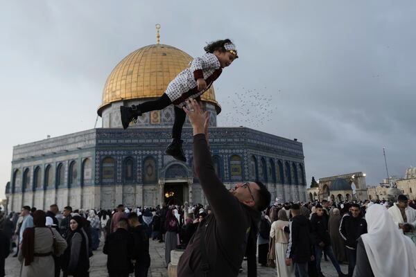 A Palestinian girl is tossed into the air as people gather for Eid al-Fitr prayers by the Dome of the Rock shrine in the Al Aqsa Mosque compound in Jerusalem's Old City, Sunday, March 30, 2025. (AP Photo/Mahmoud Illean)