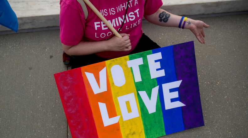 Demonstrator Catherine Nicole Struck from Frederick, Maryland, holds a "Vote Love" rainbow sign while sitting outside the U.S. Supreme Court in Washington, D.C., U.S., on Friday, June 26, 2015. The high court will decide by the end of the month whether the Constitution gives gays the right to marry. The court's actions until now have suggested that a majority of the nine justices will vote to legalize same-sex weddings nationwide. Photographer: Andrew Harrer/Bloomberg *** Local Caption *** Catherine Nicole Struck