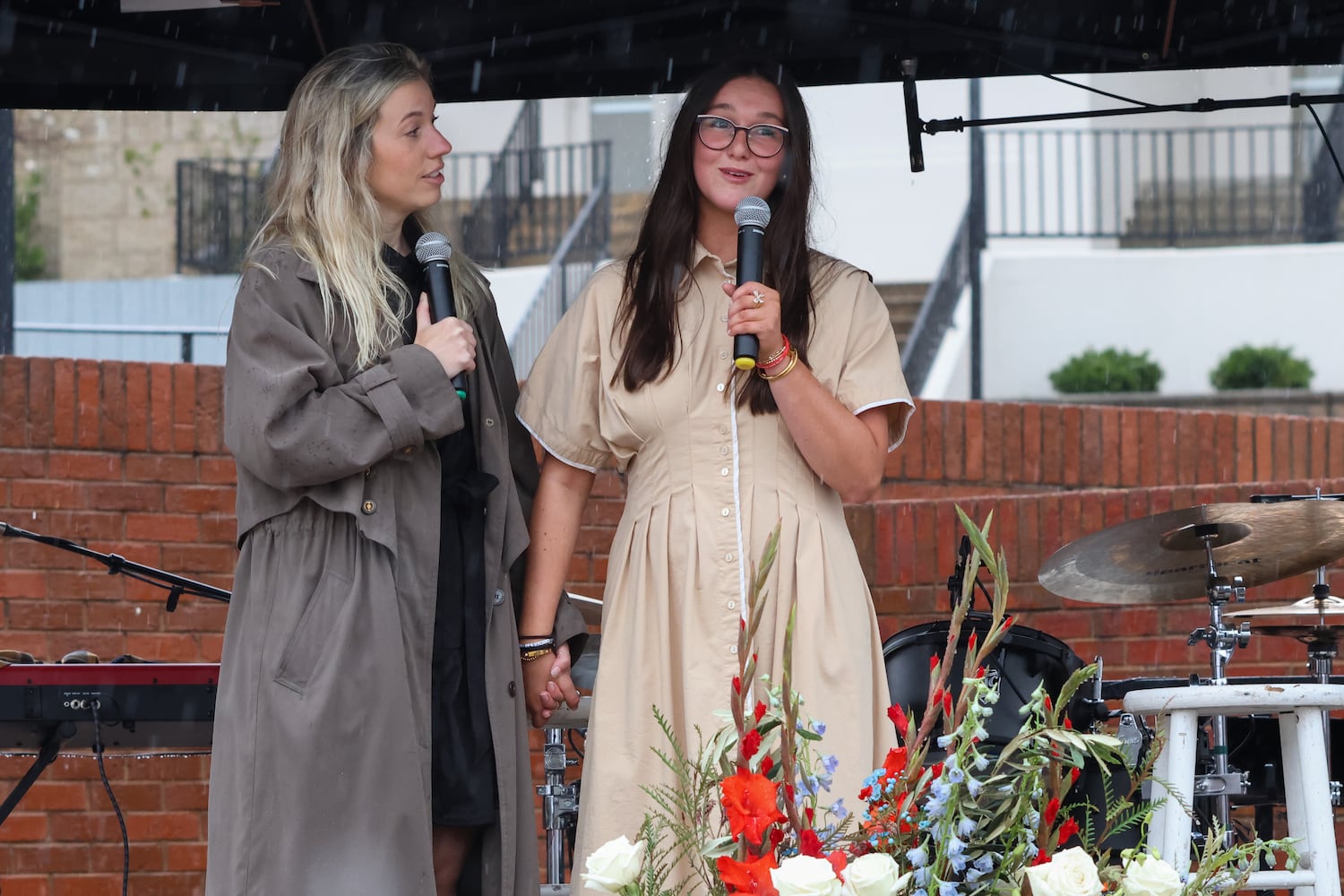 Lauren Phillips (right), Laken Riley’s younger sister, speaks at UGA’s Tate Plaza on Saturday, Feb. 21, 2026, during a memorial service for Laken Riley. Riley was attacked on Feb. 22, 2024 while running in Oconee Forest Park on the UGA campus and killed. Macy Rutledge, one of the event’s organizers, holds Phillips’ hand. Phillips recalled her sister’s warmth and religious faith and described how Laken inspired her. (C.J. Bartunek for the AJC)
