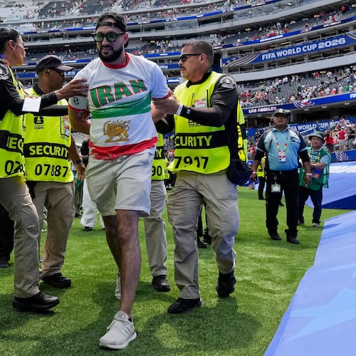 An Iranian fan is removed from the pitch by security at the end of the World Cup Group G soccer match between Belgium and Iran in Inglewood, Calif., near Los Angeles, Sunday, June 21, 2026. (AP Photo/Gregory Bull)