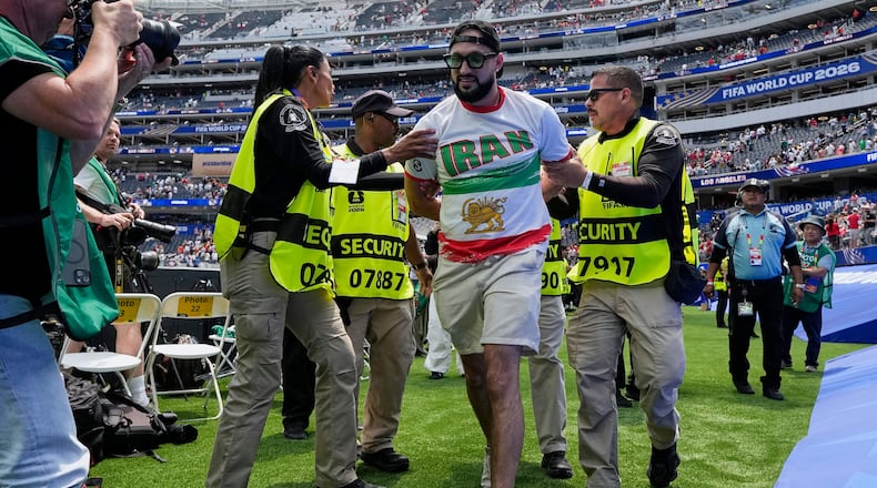 An Iranian fan is removed from the pitch by security at the end of the World Cup Group G soccer match between Belgium and Iran in Inglewood, Calif., near Los Angeles, Sunday, June 21, 2026. (AP Photo/Gregory Bull)