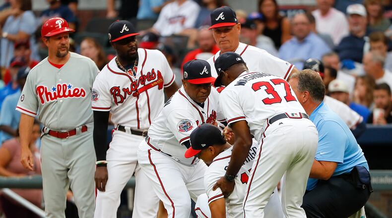 Bench coach Terry Pendleton #9, third base coach Ron Washington #37 and trainer Jim Lovell of the Atlanta Braves help up Johan Camargo #17 after he fell to the ground running onto the field in the first inning to face the Philadelphia Phillies at SunTrust Park on August 8, 2017 in Atlanta, Georgia. (Photo by Kevin C. Cox/Getty Images)