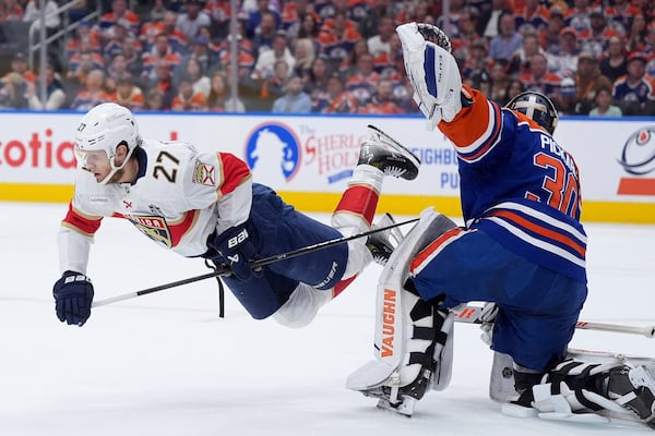 Florida Panthers center Eetu Luostarinen (27) trips over Edmonton Oilers goalie Calvin Pickard (30) during the first period in Game 5 of the NHL hockey Stanley Cup Final in Edmonton, Alberta, Saturday, June 14, 2025. (Darryl Dyck/The Canadian Press via AP)