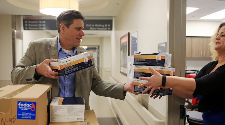 Chris Brand (left), president and CEO of FODAC, hands Laura Hochwalt, executive director of emergency and trauma at Grady Hospital, donated masks and medical supplies on Tuesday, March 24, 2020, at Grady Hospital in Atlanta. FODAC, Friends of Disabled Adults and Children, is an organization that provides wheelchairs and other medical equipment to disabled people. In the midst of the CO-VID 19 outbreak, the organization has focused on delivering masks, gloves and other in-demand supplies to hospitals. (Christina Matacotta, for The Atlanta Journal-Constitution)