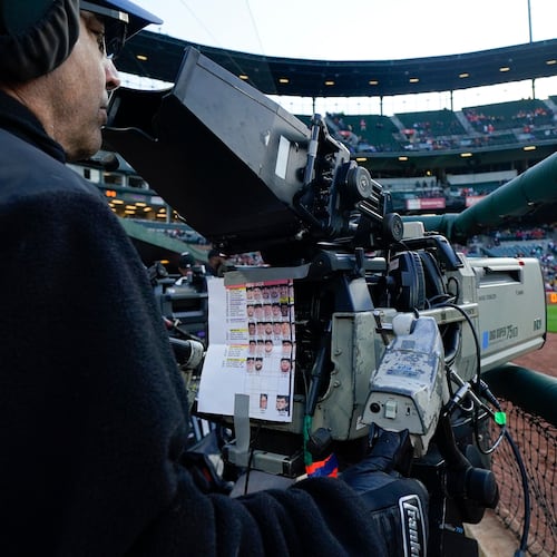 FILE - A sheet showing Boston Red Sox players photos hangs from a camera as a broadcast operator works during the first inning of a baseball game between the Baltimore Orioles and the Red Sox, Monday, April 24, 2023, in Baltimore, Md. (AP Photo/Julio Cortez, File)