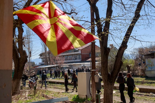 A Macedonian flag is lowered at half mast as people walk along railway tracks, heading for the funeral ceremony of the victims of a massive nightclub fire in the town of Kocani, North Macedonia, Thursday, March 20, 2025. (AP Photo/Visar Kryeziu)