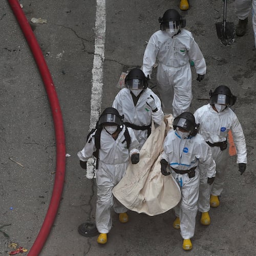 Police remove what appears to be a body bag from the site of a deadly Wednesday fire at Wang Fuk Court, a residential estate in the Tai Po district of Hong Kong's New Territories on Sunday, Nov. 30, 2025. (AP Photo/Ng Han Guan)