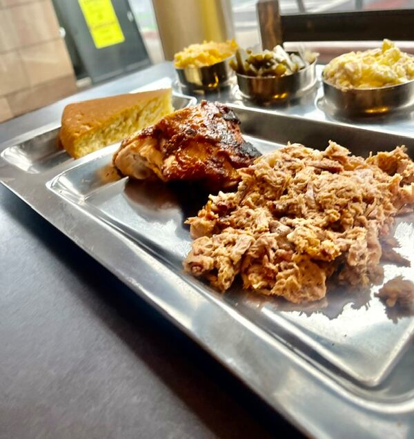 Barbecue plate with pulled pork, chicken, cornbread and sides.