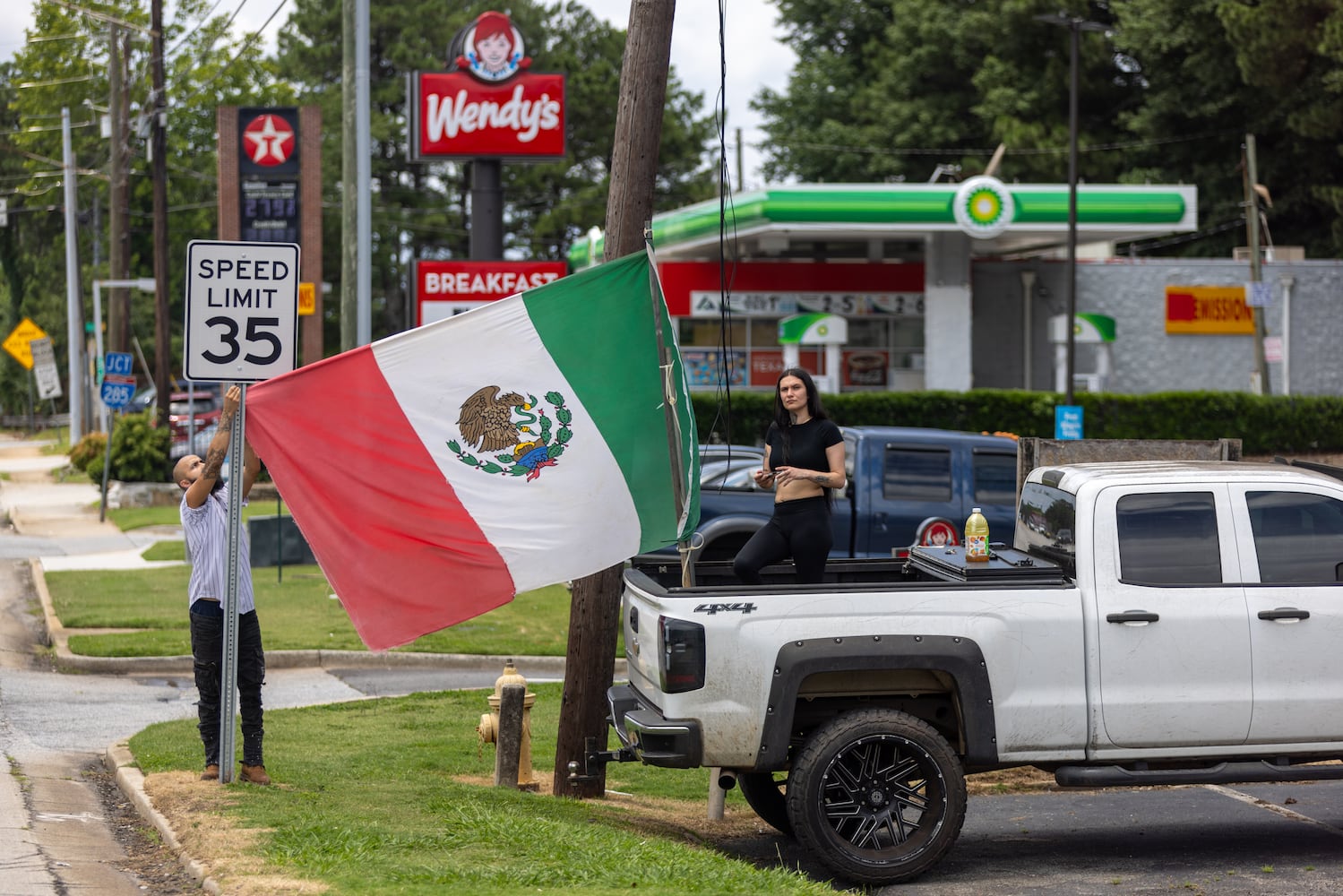 Demonstrators set up a Mexican flag during a protest on ICE raids and deportation arrests on Chamblee Tucker Road in Atlanta on Saturday, June 14, 2025. (Arvin Temkar / AJC)