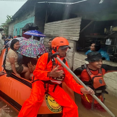 In this photo released by the Indonesian National Search and Rescue Agency (BASARNAS), rescuers on a rubber boat evacuate residents from their flooded home in North Sumatra province, Indonesia Tuesday, Nov. 25, 2025. (BASARNAS via AP)