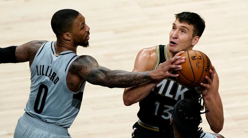 Hawks guard Bogdan Bogdanovic (13) is defended by Blazers guard Damian Lillard (0) as he tries to shoot in the first half of an NBA basketball game Monday, May 3, 2021, in Atlanta.