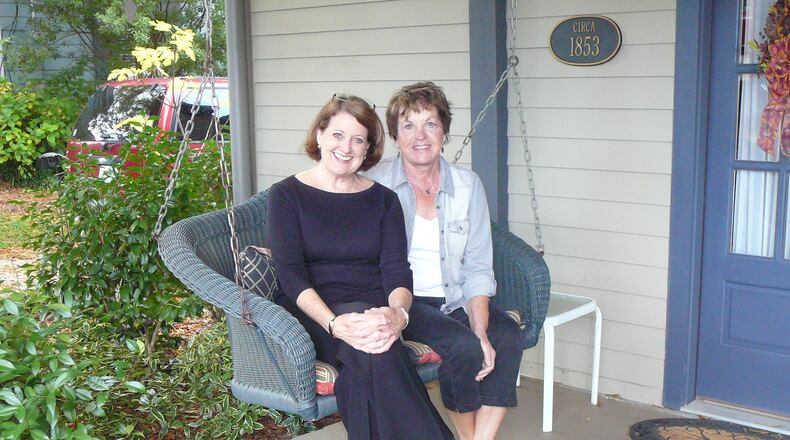 Joanne Carlton (r) and Kathleen White sit on the front porch of White's restored 1853 mill cottage in Roswell. White and her husband have opened the house to the Roswell King Social Club, started by Carlton eight years ago.