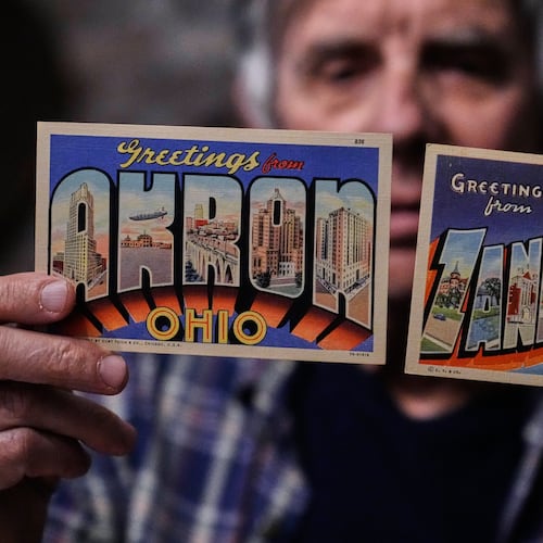 Postcard collector Peter Meggison, holds up two examples of large letter postcards from places across America going from A to Z, Akron to Zanesville, Monday, May 11, 2026, in Westport, Mass. (AP Photo/Charles Krupa)