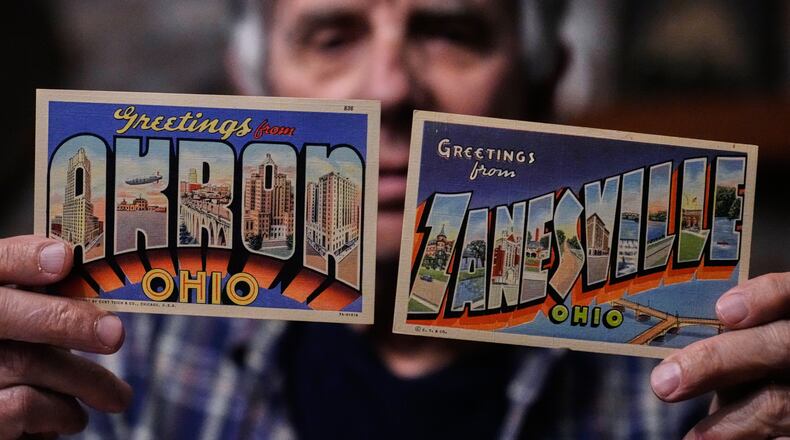 Postcard collector Peter Meggison, holds up two examples of large letter postcards from places across America going from A to Z, Akron to Zanesville, Monday, May 11, 2026, in Westport, Mass. (AP Photo/Charles Krupa)