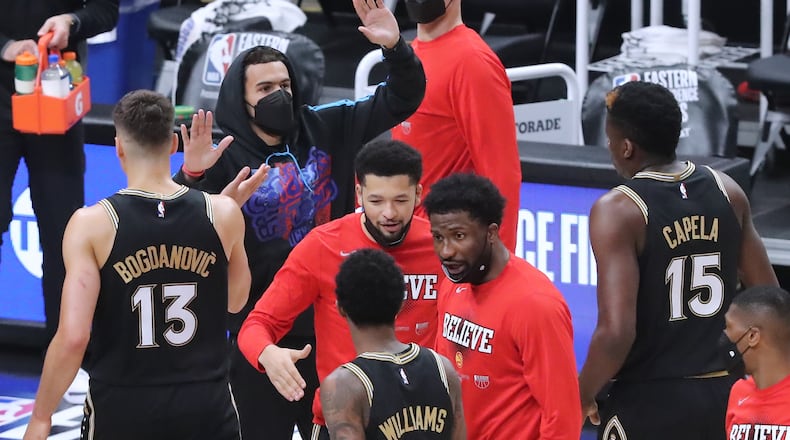 Hawks' injured guard Trae Young gives teammates high fives as they take the early lead against the Milwaukee Bucks during the first quarter of Game 4 of the Eastern Conference finals Tuesday, June 29, 2021, at State Farm Arena in Atlanta. (Curtis Compton / Curtis.Compton@ajc.com)