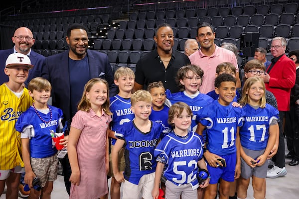 Team owners Jerome Bettis, second man from eft, Brian Jordan and David Pollack pose for a photograph with youth football players and others during the Athens Football Kickoff celebration at the Akins Ford Arena. (Jason Getz/AJC)