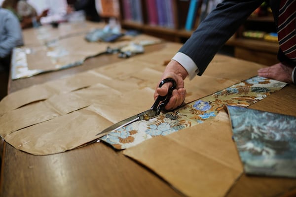 A tailor uses a pattern to cut fabric at the Gammarelli ecclesiastic clothes tailor shop in Rome, Wednesday, April 30, 2025. (AP Photo/Francisco Seco)