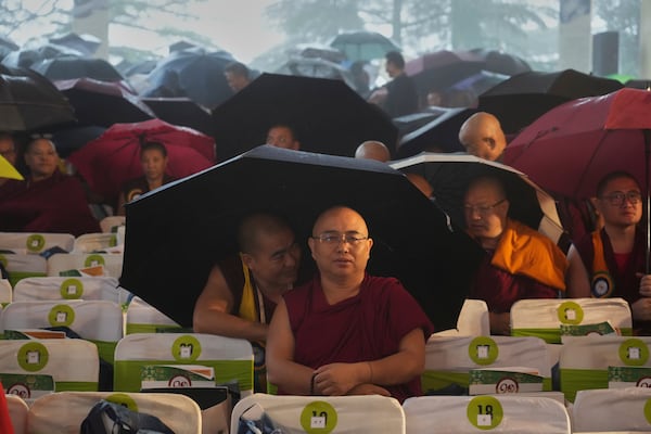 Devotees wait in the rain for the arrival of Tibetan spiritual leader the Dalai Lama to attend an event celebrating his 90th birthday in Dharamshala, India, Sunday, July 6, 2025. (AP Photo/Ashwini Bhatia)