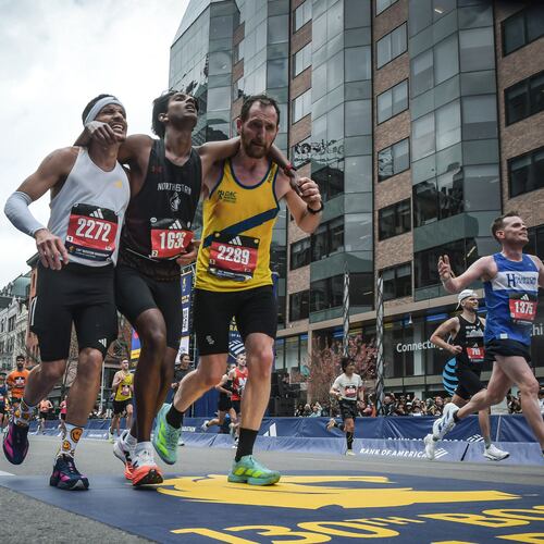 This photo provided by the Boston Athletic Association and Marathonfoto shows Boston Marathon runners Robson De Oliveira of Brazil, left, and Aaron Beggs, of Britain, right, helping runner Ajay Haridasse and helped him across the finish line Monday, April 20, 2026, in Boston. (Gustavo E. Gargallo/Boston Athletic Association/MarathonFoto via AP)
