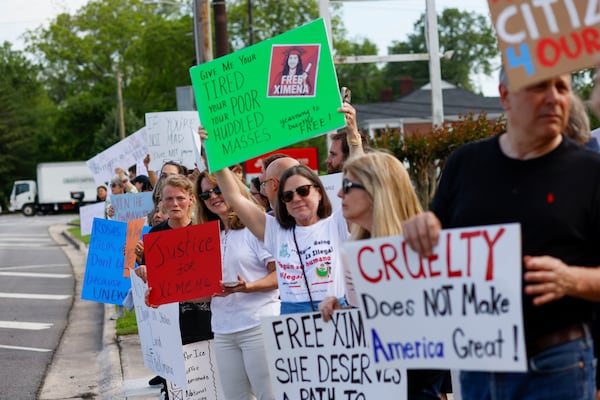 Protesters hold up homemade signs as cars zoomed by, many honking in support, on a busy street near Dalton's downtown on Wednesday. (Miguel Martinez/AJC)