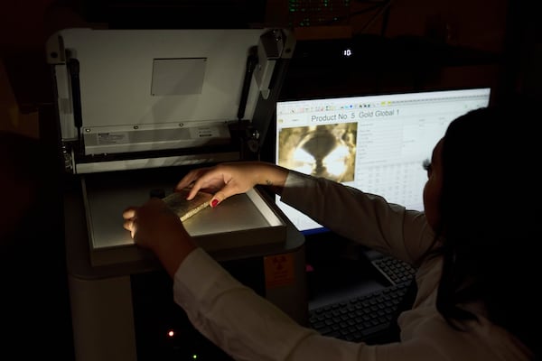 Sarahi Cervantes places a gold bar on an X-ray machine for assaying at A&M Precious Metals in the St. Vincent Jewelry Center in the Jewelry District of Los Angeles, Friday, May 2, 2025. (AP Photo/Jae C. Hong)