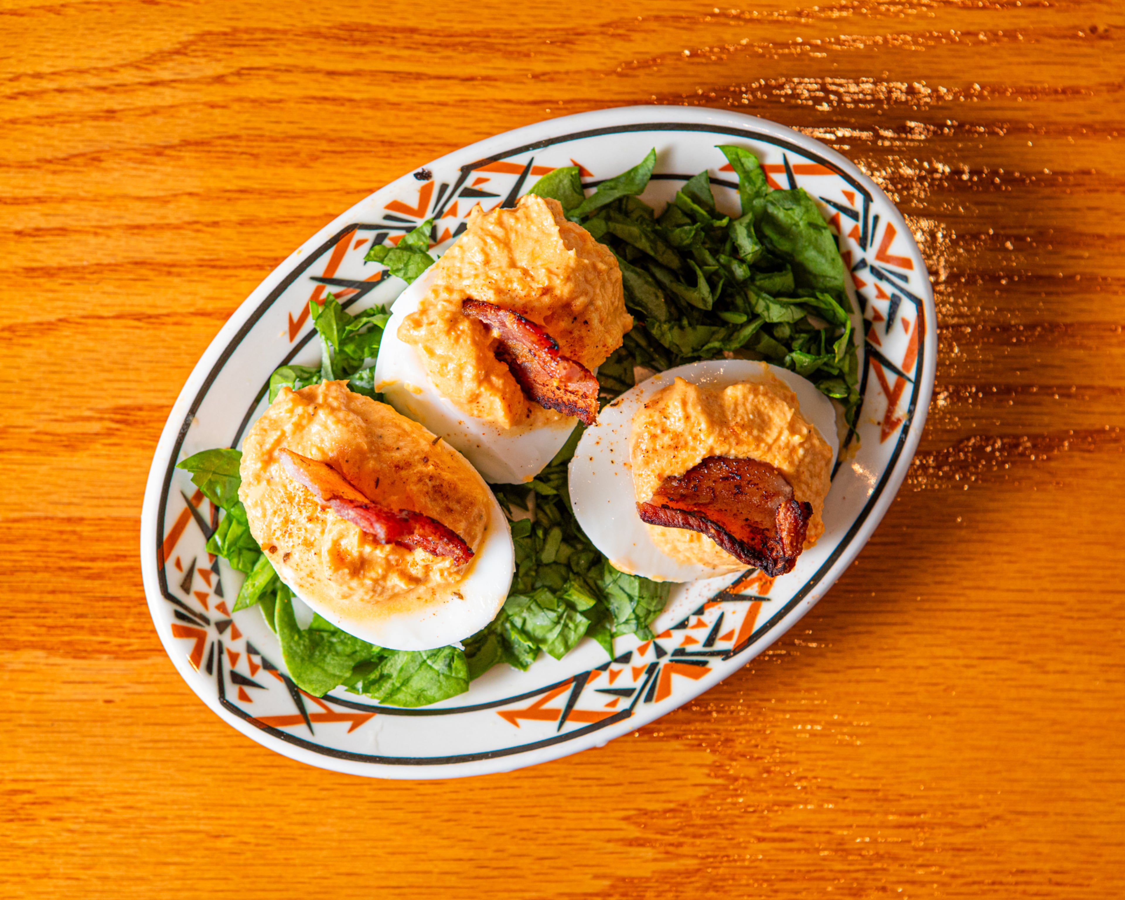 Celebrate Labor Day with something new: deviled eggs made with sweet potato, sour cream and a candied bacon garnish. (Aaliyah Man for the AJC/food styling by Michele Tomkins)