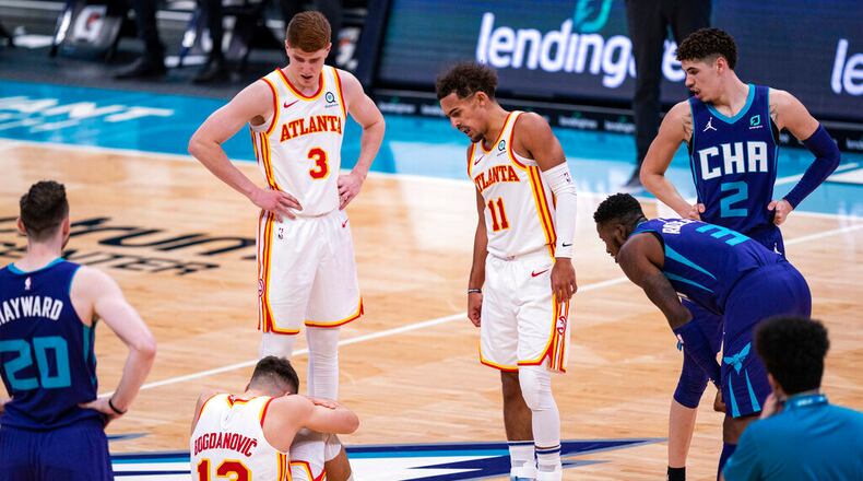 Atlanta Hawks guard Bogdan Bogdanovic (13) sits on the court after being fouled by Charlotte Hornets guard LaMelo Ball (2) during the first half of an NBA basketball game in Charlotte, N.C., Saturday, Jan. 9, 2021. (AP Photo/Jacob Kupferman)