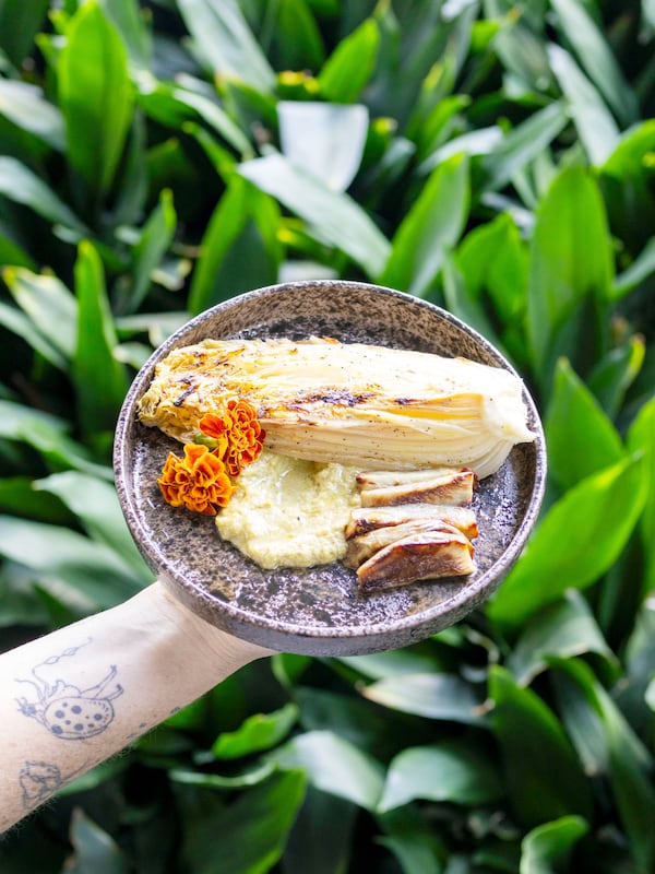 Bowl of food topped with shredded vegetables and herbs