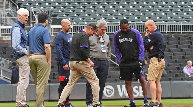 Officials survey the field before the Braves' game against the Colorado Rockies was postponed on Thursday. (Hyosub Shin / Hyosub.Shin@ajc.com)