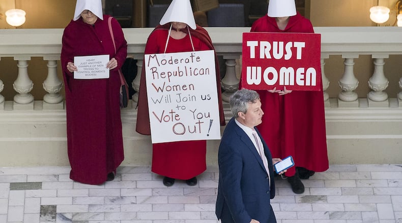 A man walks past abortion rights advocates protesting against House Bill 481, the “heartbeat bill” that would outlaw most abortions in Georgia. (ALYSSA POINTER/ALYSSA.POINTER@AJC.COM)