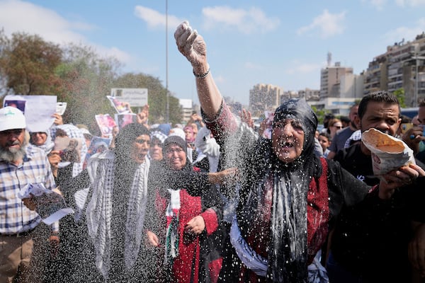 A woman throws flour, as she protests outside the Egyptian Embassy in Beirut, Lebanon, Wednesday, July 23, 2025, during a demonstration against the Israeli war and what they say starvation of civilians in the Gaza Strip. (AP Photo/Hussein Malla)