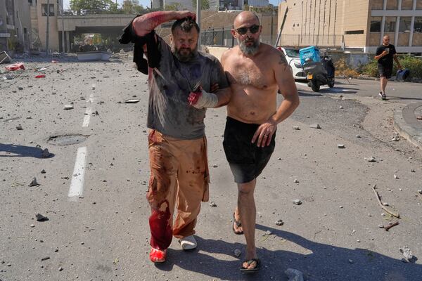 An injured man is helped to leave after a missile hit from Iran, in Haifa, Israel, Friday, June 20, 2025. (AP Photo/Baz Ratner)