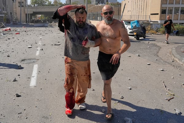 An injured man is helped to leave after a missile hit from Iran, in Haifa, Israel, Friday, June 20, 2025. (AP Photo/Baz Ratner)