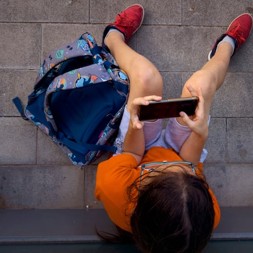 FILE - A child plays with his father's phone outside a school in Barcelona, Spain, Monday, June 17, 2024. (AP Photo/Emilio Morenatti, File)