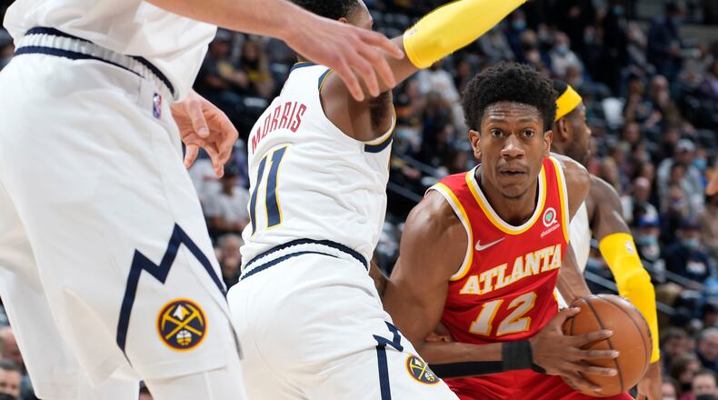 Atlanta Hawks forward De'Andre Hunter, right, looks to pass the ball as Denver Nuggets guard Monte Morris defends during the first half of an NBA basketball game Friday, Nov. 12, 2021, in Denver. (AP Photo/David Zalubowski)