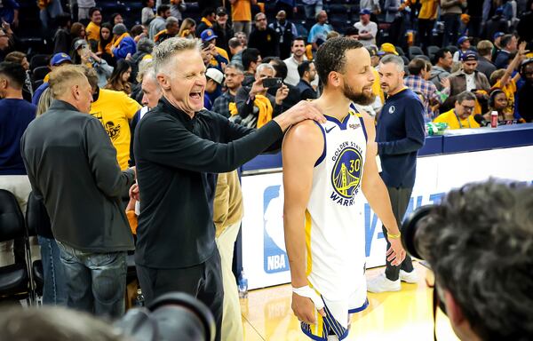 Golden State Warriors head coach Steve Kerr celebrates with Stephen Curry (30) after the Golden State Warriors defeated the Memphis Grizzlies 121-116 in the NBA play-in game at Chase Center in San Francisco, on Tuesday, April 15, 2025. (Carlos Avila Gonzalez/San Francisco Chronicle via AP)