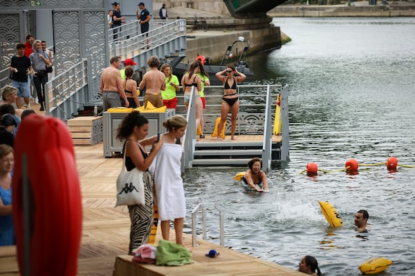 A woman dives in the water as people swim at the Pont Marie safe bathing site on the Seine river in Paris, France, Saturday, July 5, 2025, during the opening of the three Seine swimming pools, as part of the 'Paris Plages' event. (AP Photo/Thomas Padilla)
