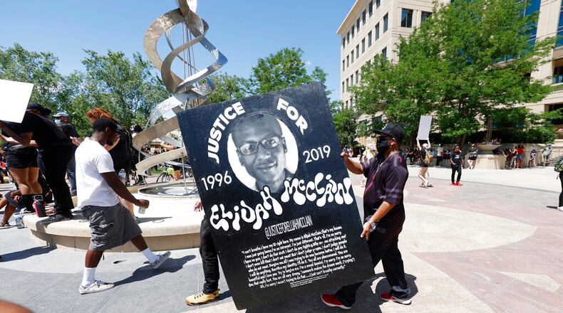 Demonstrators carry a giant placard during a rally and march over the death of 23-year-old Elijah McClain, Saturday, June 27, 2020, outside the police department in Aurora, Colo. McClain died in late August 2019 after he was stopped while walking to his apartment by three Aurora Police Department officers. (AP Photo/David Zalubowski)