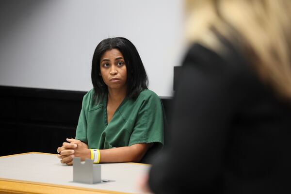 Deja Coleman, the mother charged in the death of her baby after officials said he was left in a hot vehicle, listens to prosecutor Megan Matteucci, right, during a hearing on Tuesday, Aug. 11, 2026, in Lawrenceville. (Jason Getz/AJC)
