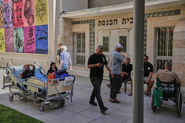 Patients rest outdoors after a building of the Soroka hospital complex was hit by a missile fired from Iran in Be'er Sheva, Israel, Thursday, June 19, 2025. (AP Photo/Leo Correa)