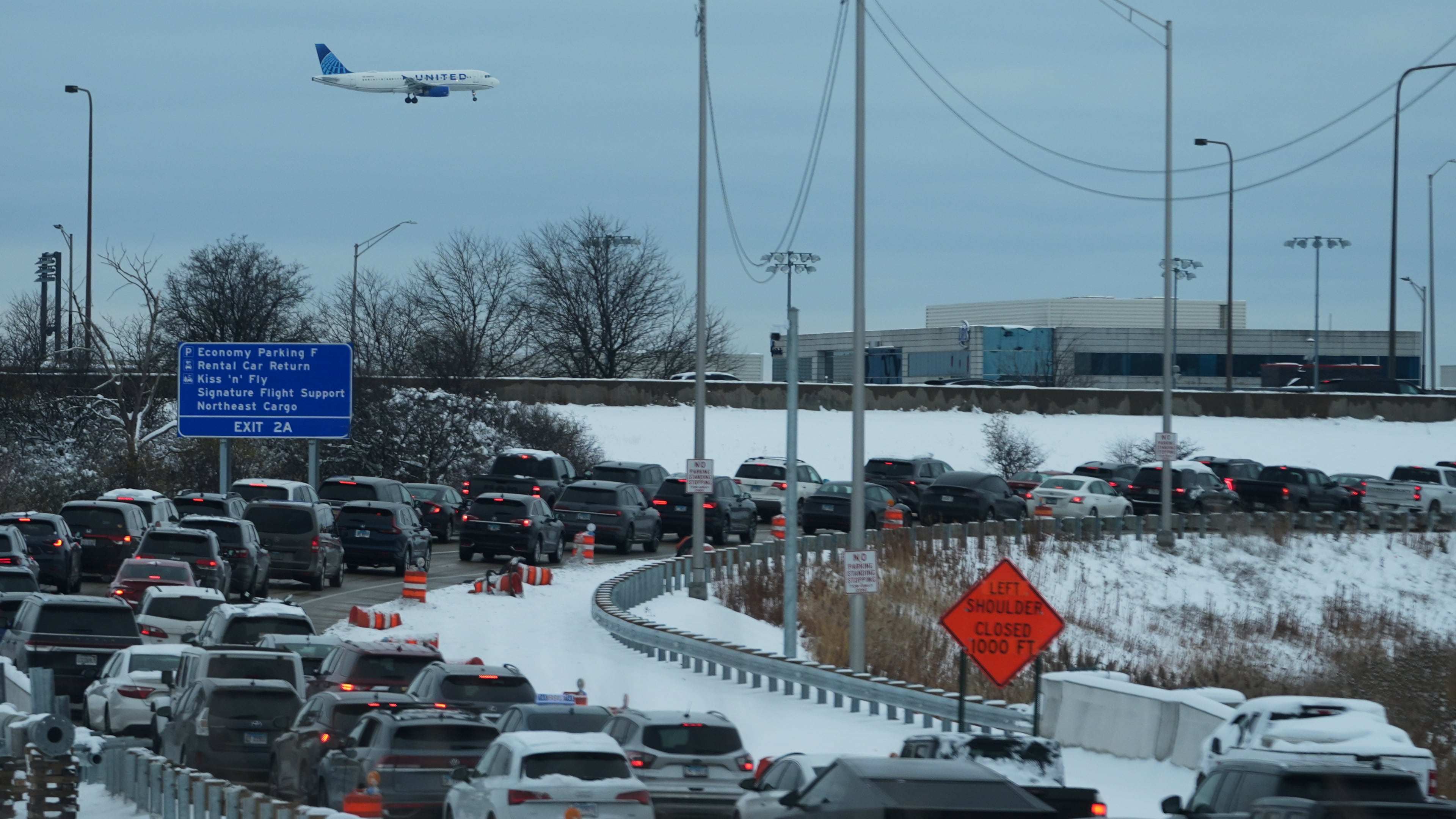 An United airplane descends to land at O'Hare International Airport as heavy traffic is seen on highway to airport in Chicago, Sunday, Nov. 30, 2025. (AP Photo/Nam Y. Huh)