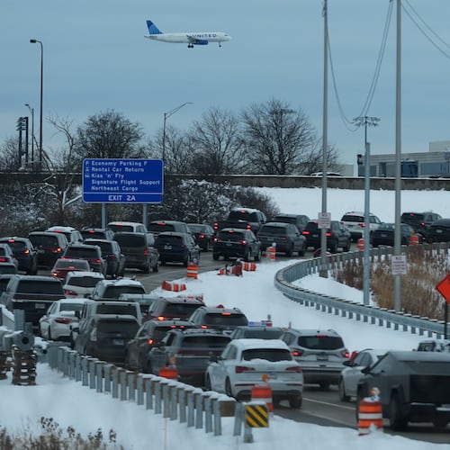 An United airplane descends to land at O'Hare International Airport as heavy traffic is seen on highway to airport in Chicago, Sunday, Nov. 30, 2025. (AP Photo/Nam Y. Huh)