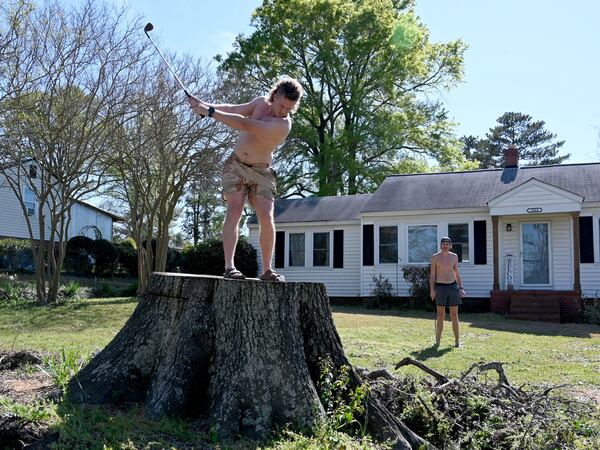 Not far from Augusta National, Obie Brannon hits a golf ball from the stump of a tree downed during Hurricane Helen.