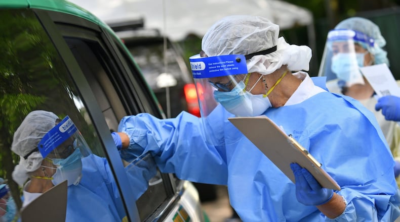 A medical professional collects a nasal swab from a potential COVID-19 patient at a drive-through COVID-19 testing site at Good News Clinic in Gainesville on Tuesday, April 28, 2020. HYOSUB SHIN / HYOSUB.SHIN@AJC.COM