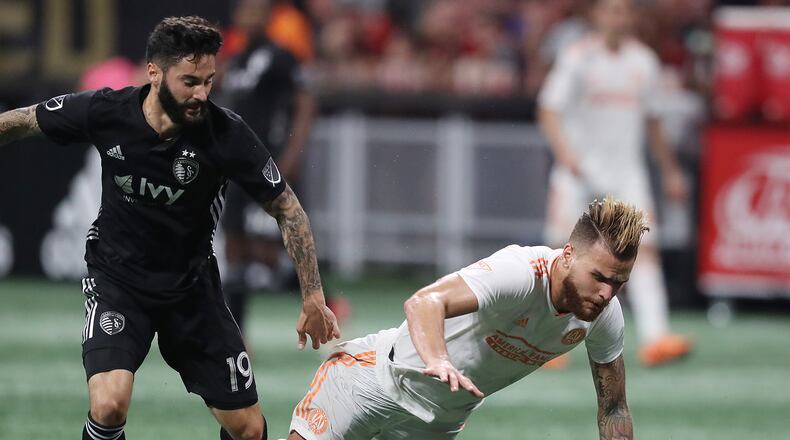 Atlanta United defender Leandro Gonzalez Pirez is tripped up by Sporting Kansas City midfielder Cristian Lobato during the second half Wednesday night at the Benz. (Curtis Compton/ccompton@ajc.com)