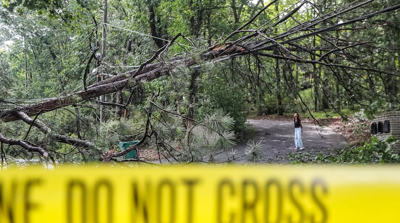 Anna Maria De Diego looks over a downed tree hanging across electrical wires in front of her home on Spalding Road near Hewlett Drive in Sandy Springs.